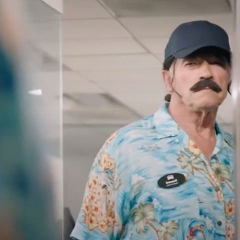 Arnold Schwarzenegger im bunten Hemd mit Schnurrbart und Cap.