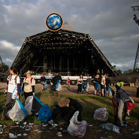 Mit Müllbeuteln ausgestattet, räumen Helfer das Festivalgelände auf