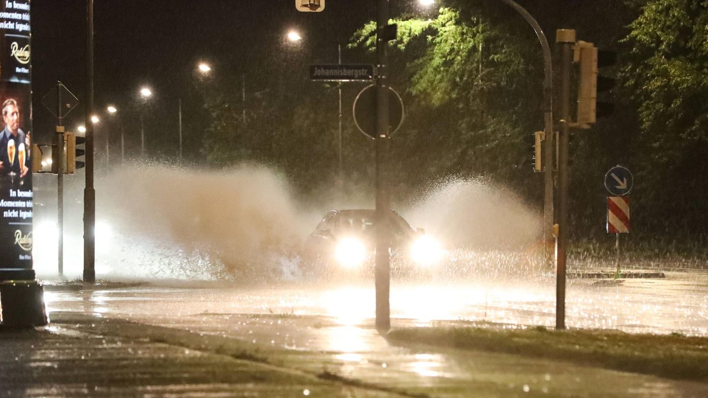 Ein Auto am Petriförder spritzt das Regenwasser durch die Luft - Unwetter mit Starkregen und Gewitter.