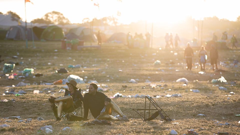Glastonbury Festival Erschöpft sitzen Besucher des Festival auf der Wiese