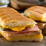 Cuban Sandwich  Das vor allem im Süden der USA beliebten Sandwich wird auch Cubano genannt. Und es kommt nicht, wie der Name vermuten lässt, aus Kuba. Aber Kubaner haben ein ähnliches Sandwich mit Fisch und Cassava-Brot gemacht, die Spanier brachten den Käse, das Weißbrot und das Schweinefleisch dazu. Anfang der 1800er Jahre florierte der Tabakimport zwischen Kuba und Südflorida. Die Arbeiter brauchten einen schnellen Snack, so wurde das Sandwich geboren. Heute kennt man das Cubano mit gebratenem Schweinefleisch, Schinken, Schweizer Käse und Essiggurke. 