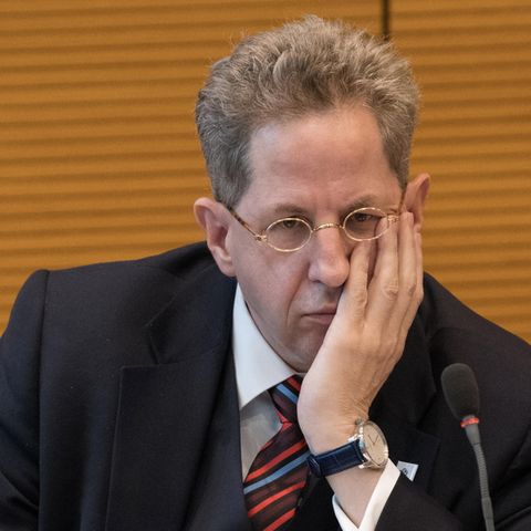 Hans-Georg Maaßen sitzt im Anzug vor einer gelblichen Wand und stützt seinen Kopf in die linke Hand