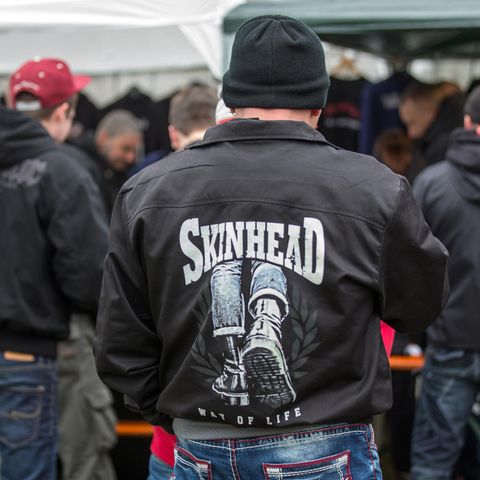 Publikum in schwarzen Jacken mit Skinhead-Logos