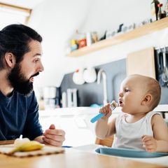 Vater guckt sein Kind beim Essen an