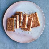 Himberschnitten  Zutaten: 375 g Weizenmehl Type 405, 75 g gemahlene Mandeln, 200 g Zucker, Mark von 1 Vanilleschote, 275 g kalte Butter, gewürfelt, 1 Ei, verquirlt, 1 Eigelb, mit 2 EL Milch verquirlt, zum Bepinseln, 500 g Himbeermarmelade, 50 g Demarara-Zucker      Zubereitung: Das Mehl, die gemahlenen Mandeln, den Zucker und das Vanillemark in einer Küchenmaschine gut vermischen. Die Butter dazugeben und alles zu feinen Streuseln verarbeiten. Das verquirlte Ei nach und nach zur Mehl-Butter-Mischung geben, bis diese zu einem glatten Teig wird. Den Teig zu einer Platte formen und in zwei gleichgroße Stücke teilen. Diese jeweils zu einer etwa 3 cm dicken Platte formen, abdecken und 30 Minuten in den Kühlschrank stellen. Die Teigplatten jeweils zwischen 2 Bögen Backpapier legen und 3 mm dick ausrollen. Mit dem Backpapier 30 Minuten kalt stellen. Den Ofen auf 190 °C (Ober-/Unterhitze) vorheizen. Das Backpapier entfernen, die Teigplatten auf die Arbeitsfläche legen und mehrmals mit einer Gabel einstechen. Eine Teigplatte auf ein mit Backpapier versehenes Backblech legen und die Marmelade daraufstreichen, dabei einen 2 cm breiten Rand lassen. Die zweite Teigplatte auf der Marmelade platzieren und von der Mitte her vorsichtig nach außen streichen, damit beide Teigplatten dicht aufeinander liegen. Mehrfach mit einer Gabel einstechen. Die Teigoberfläche mit dem mit Milch verquirlten Eigelb bepinseln und den Demarara-Zucker darübersprenkeln. 20–25 Minuten backen, bis der Teig eine appetitliche goldbraune Farbe angenommen hat. In Rechtecke schneiden, wenn der Kuchen bereits etwas abgekühlt, aber immer noch leicht lauwarm ist. Auf einem Kuchengitter vollständig abkühlen lassen.