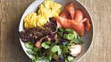Geräucherter Lachs  Zutaten: 100 g altbackenes Roggenbrot, sehr dünn geschnitten, 50 g Parmesan, fein gerieben, 4 EL Buttermilch, 2 EL Traubenkernöl, 2 EL Apfelessig, 1 EL Schnittlauch, gehackt, 1 EL glatte Petersilie, gehackt, Salz, schwarzer Pfeffer aus der Mühle, 4 große Bio-Eier, 1 Schuss Milch, 15 g Butter, 150 g heißgeräucherter Lachs, 75 g Erbsenranken, 50 g junger roter Spinat, 50 g Wasserkresse, 150 g kaltgeräucherter Lachs      Zubereitung:  Den Ofen auf 180 °C (Ober-/Unterhitze) vorheizen. Das Brot dünn mit Öl bepinseln und mit Parmesan bestreuen. Auf ein mit Backpapier ausgelegtes Backbleich legen. 20 Minuten backen, bis es knusprig geworden ist.  In der Zwischenzeit ein Dressing aus der Buttermilch, dem Öl und dem Essig herstellen. Den Schnittlauch und die Petersilie untermischen und nach Belieben mit Salz und Pfeffer abschmecken.  Die Eier in einer Schüssel verquirlen, dann Milch und Salz zugeben und 1–2 Minuten schaumig schlagen.  Die Butter in einer Bratpfanne (Durchmesser 20 cm) erhitzen, bis sie leicht schäumt. Die Eier zugeben und 1–2 Minuten stocken lassen, dann mit einem Spatel von den Seiten aus in die Mitte schieben, so dass die noch flüssige Eimasse seitlich zu den Rändern herausläuft. Diesen Vorgang wiederholen, bis die Eier gestockt, aber noch nicht ganz fest sind.  Den heißgeräucherten Lachs vorsichtig mit einer Gabel in eine Schüssel zerteilen. 2–3 EL des Dressings und die Salatblätter dazugeben und alles vorsichtig schwenken.  Zum Anrichten den Salat mit dem heißgeräucherten Lachs auf zwei Schalen aufteilen, dann den kaltgeräucherten Lachs und dann das Rührei dazugeben. Zum Schluss die Roggencroutons obenauf legen und mit dem übrigen Dressing servieren.