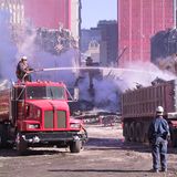 Ein Arbeiter sitzt auf einem Tankwagen und löscht den aufsteigenden Staub aus dem Schutt