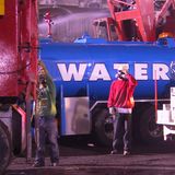 Ein Arbeiter mit Atemschutzmaske vor einem Wassertank