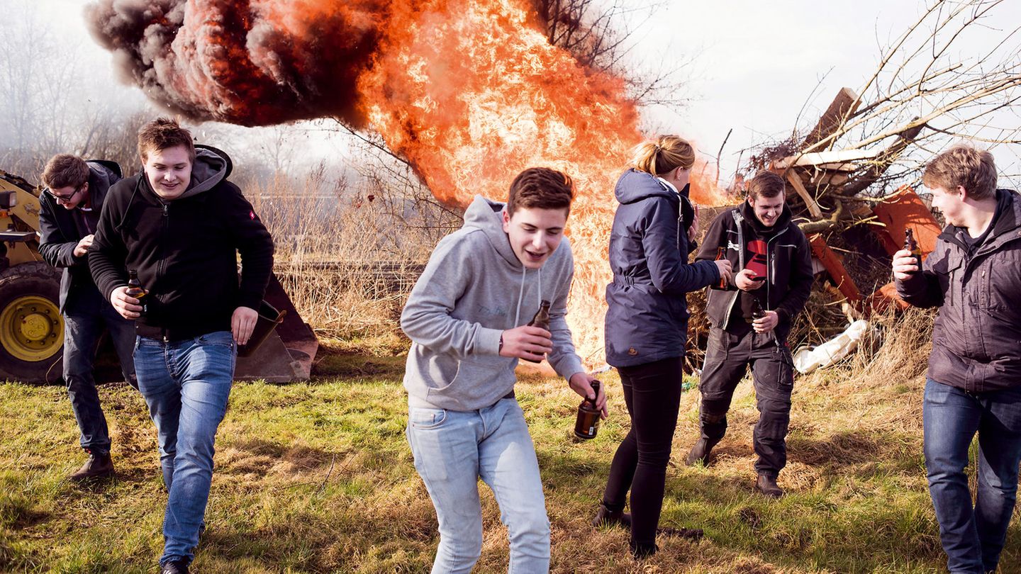 Jugendliche rennen vor einem großen Feuer davon