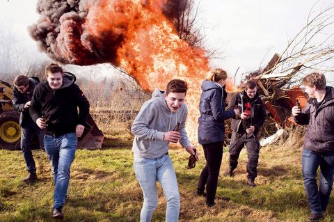 Jugendliche rennen vor einem großen Feuer davon