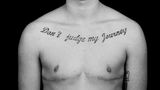 Ein Transmann mit Tattoo auf der Brust