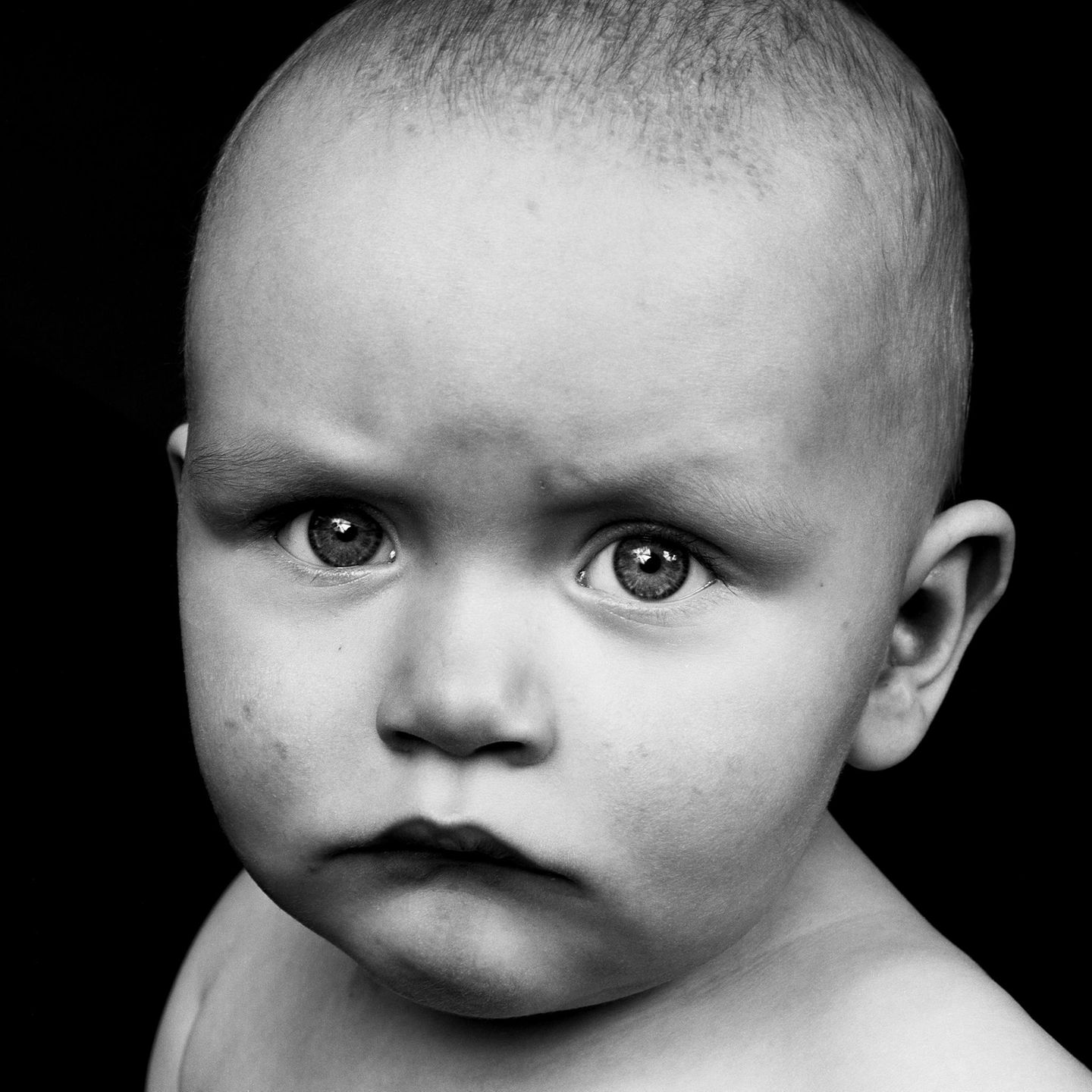 Ein Baby schaut mit hochgezogenen Augenbrauen ernst in die Kamera