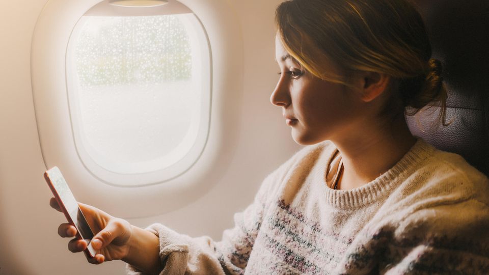 Frau mit Handy in Flugzeug