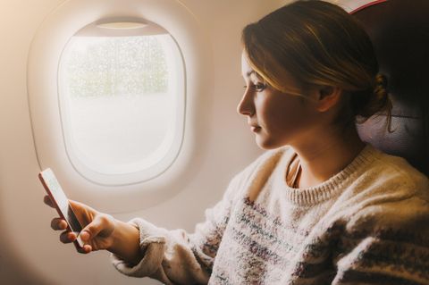 Frau mit Handy in Flugzeug