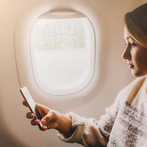 Frau mit Handy in Flugzeug