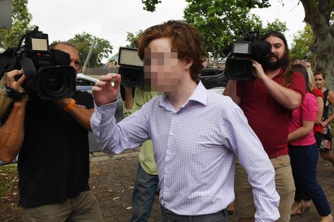 Ein junger Mann mit rotbraunem Seitenscheitel und im Karohemd geht an mehreren Kameraleuten vorbei