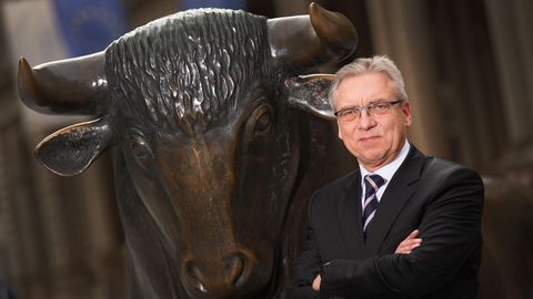 Fachanwalt Klaus Nieding steht vor einer bronzenen Bullen-Statue.
