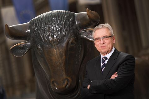 Fachanwalt Klaus Nieding steht vor einer bronzenen Bullen-Statue.