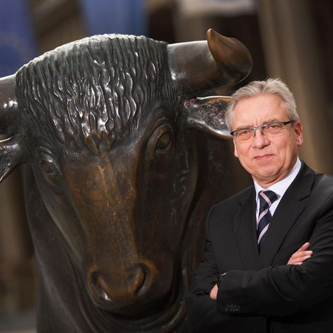 Fachanwalt Klaus Nieding steht vor einer bronzenen Bullen-Statue.