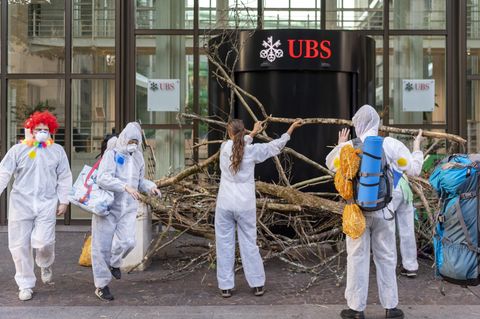 Schweiz, Basel: Aktivisten der Gruppe "Collective Climate Justice" blockieren mit Ästen den Eingang von dem UBS-Hauptsitz
