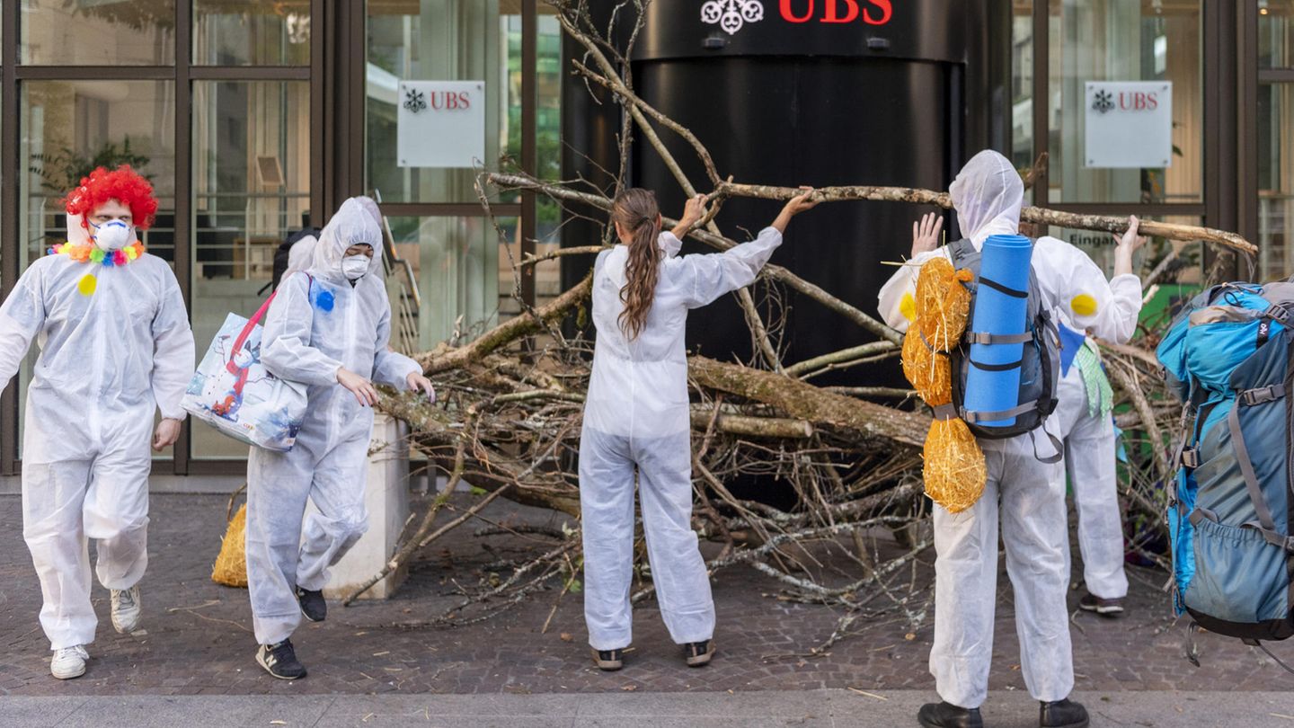 Schweiz, Basel: Aktivisten der Gruppe "Collective Climate Justice" blockieren mit Ästen den Eingang von dem UBS-Hauptsitz