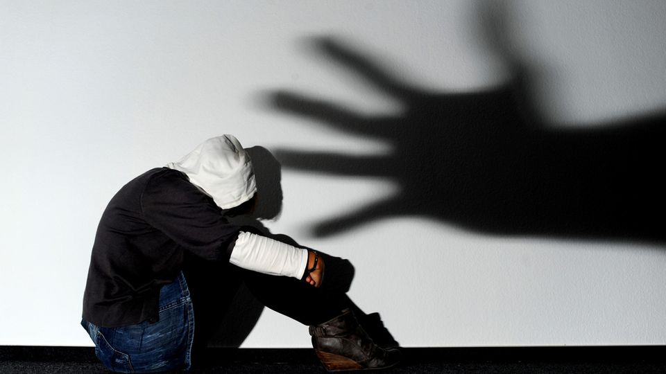 Der Schatten einer Hand über einer verängstigten jungen Frau