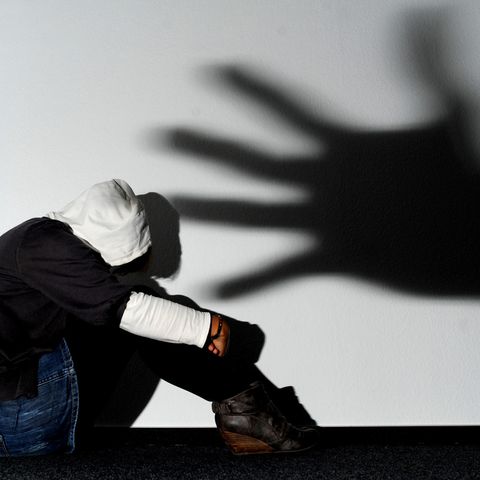 Der Schatten einer Hand über einer verängstigten jungen Frau