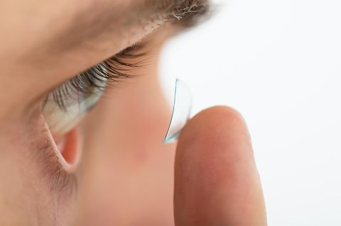 Ein Mann setzt sich mit einem Finger eine Kontaktlinse ein