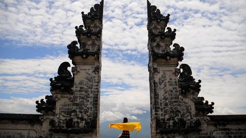 Eine Frau mit einem gelben Tuch steht zwischen den Säulen des Tempels