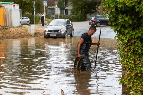 Ein Feuerwehrmann sucht nach einem Starkregen nach dem Ablauf