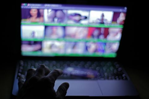 Ein Laptop-Bildschirm im Dunkeln zeigt eine Porno-Webseite