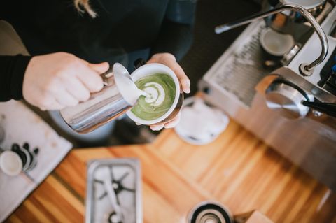 Frau grießt Milch in eine Tee-Tasse