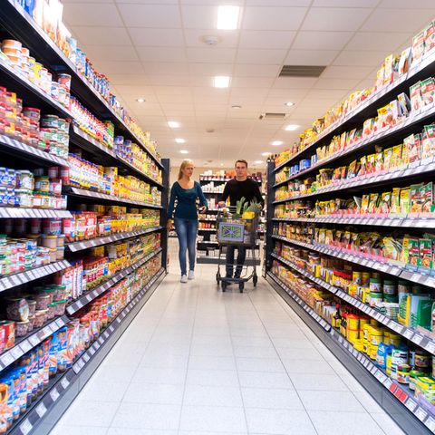 Ein Paar schiebt einen Einkaufswagen durch den Supermarkt