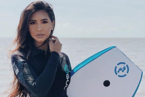 Die 21-jährige Aysha Khan posiert im Neoprenanzug mit Surfbrett