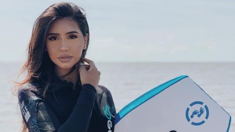 Die 21-jährige Aysha Khan posiert im Neoprenanzug mit Surfbrett