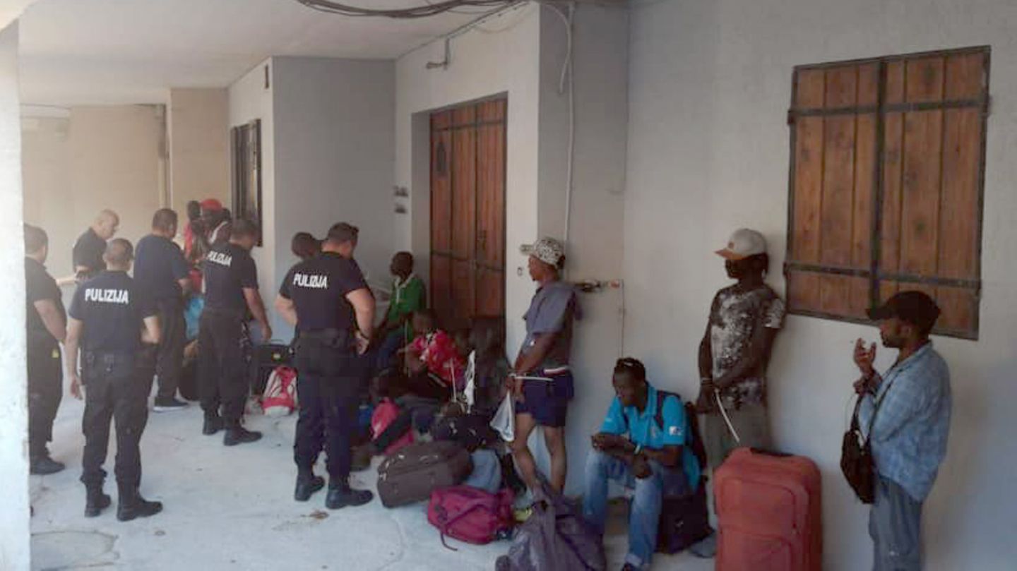 Polizisten und Migranten vor der Unterkunft in einem ehemaligen Pferdestall.