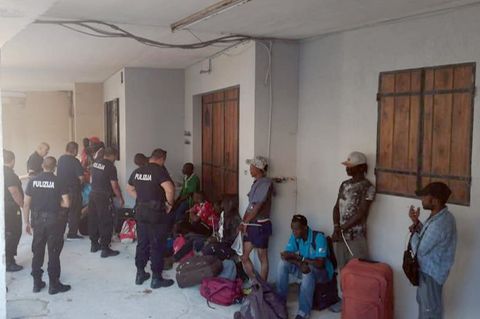 Polizisten und Migranten vor der Unterkunft in einem ehemaligen Pferdestall.