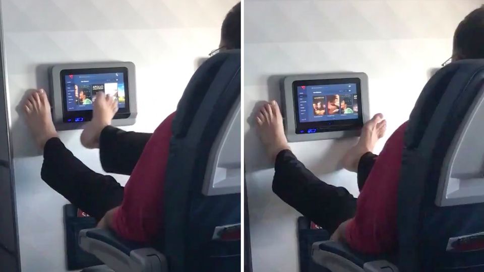 Mann bedient Entertainment-System im Flieger mit den Füßen Mann bedient Entertainment-System im Flieger mit den Füßen