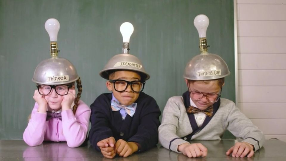 Drei Kinder mit Helmen und Glühbirnen auf dem Kopf