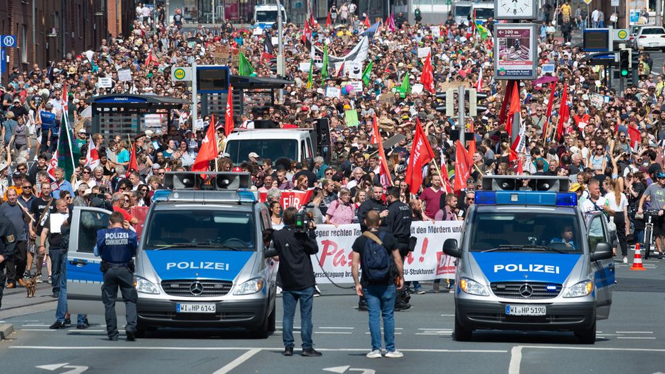 Kassel: Teilnehmer einer Gegendemonstration gehen mit Plakaten und Flaggen durch die Stadt