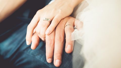 Zwei Hände mit Eheringen liegen liebevoll aufeinander