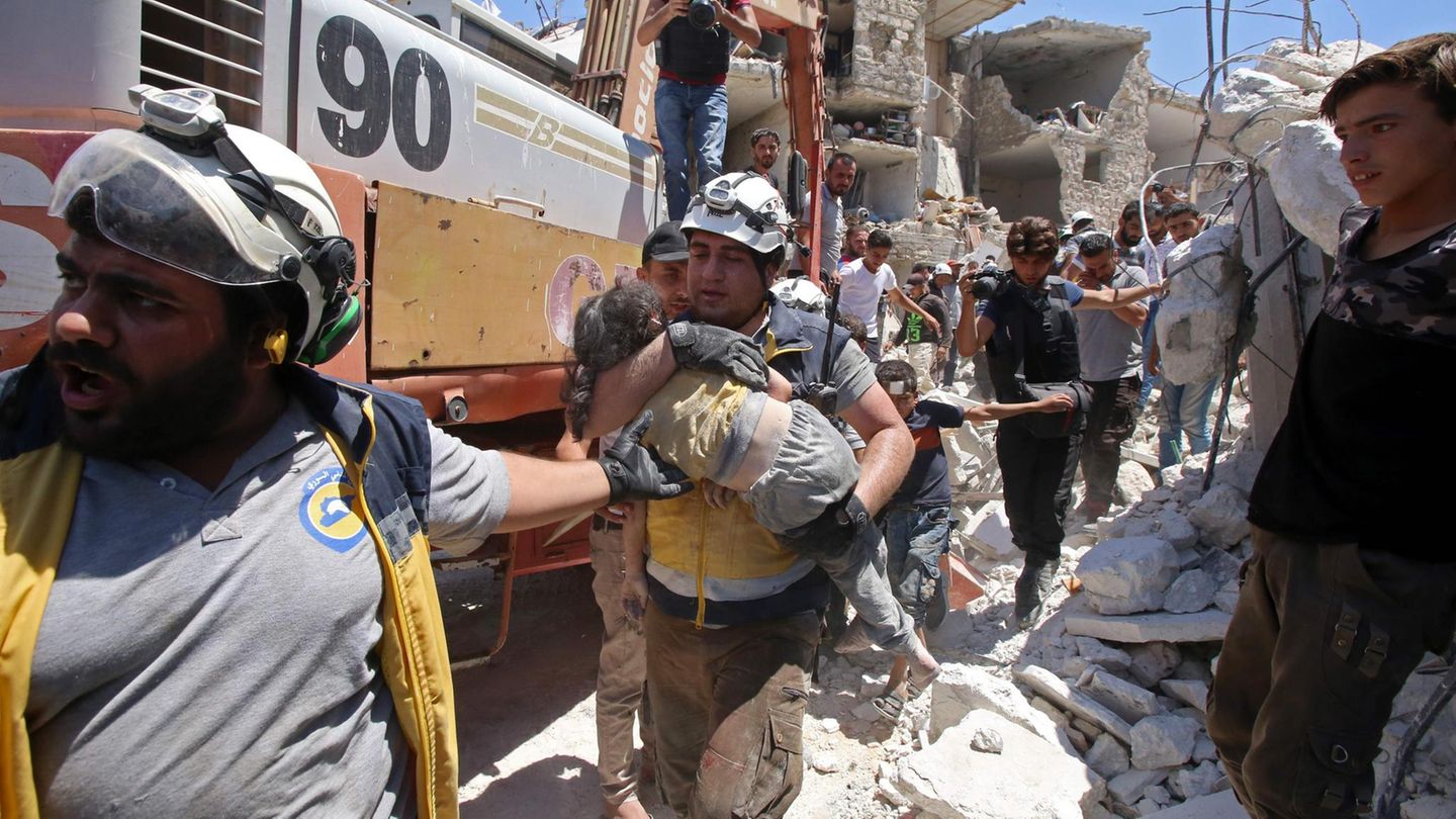 Mitglieder der Weißhelme tragen ein verletztes Kind aus den Trümmern