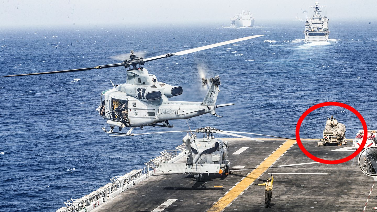 Auf der Landefläche des Kampfschiffs hebt ein Hubschrauber ab. Im Hintergrund steht das LMADIS-System