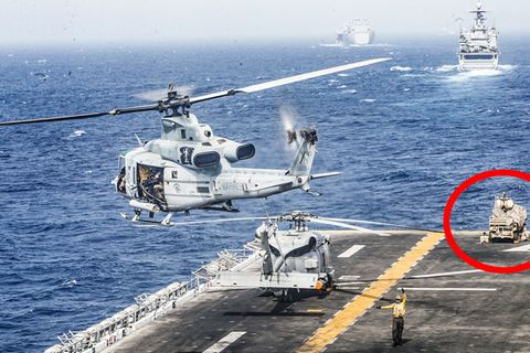 Auf der Landefläche des Kampfschiffs hebt ein Hubschrauber ab. Im Hintergrund steht das LMADIS-System