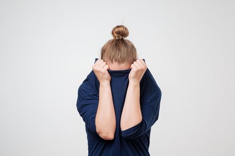 Frau versteckt sich unter Pullover