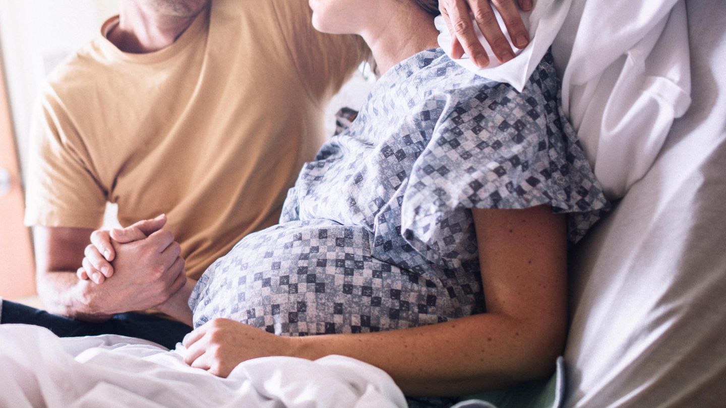 Ein Paar hält sich an der Händen, die Frau ist schwanger