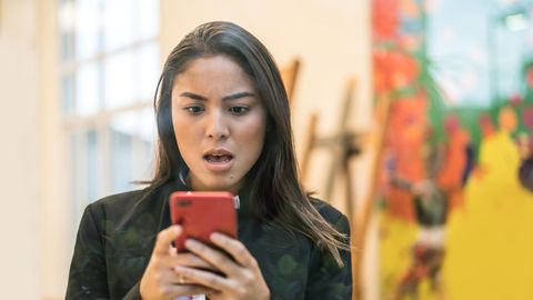Eine Frau schaut überrascht auf ihr Smartphone
