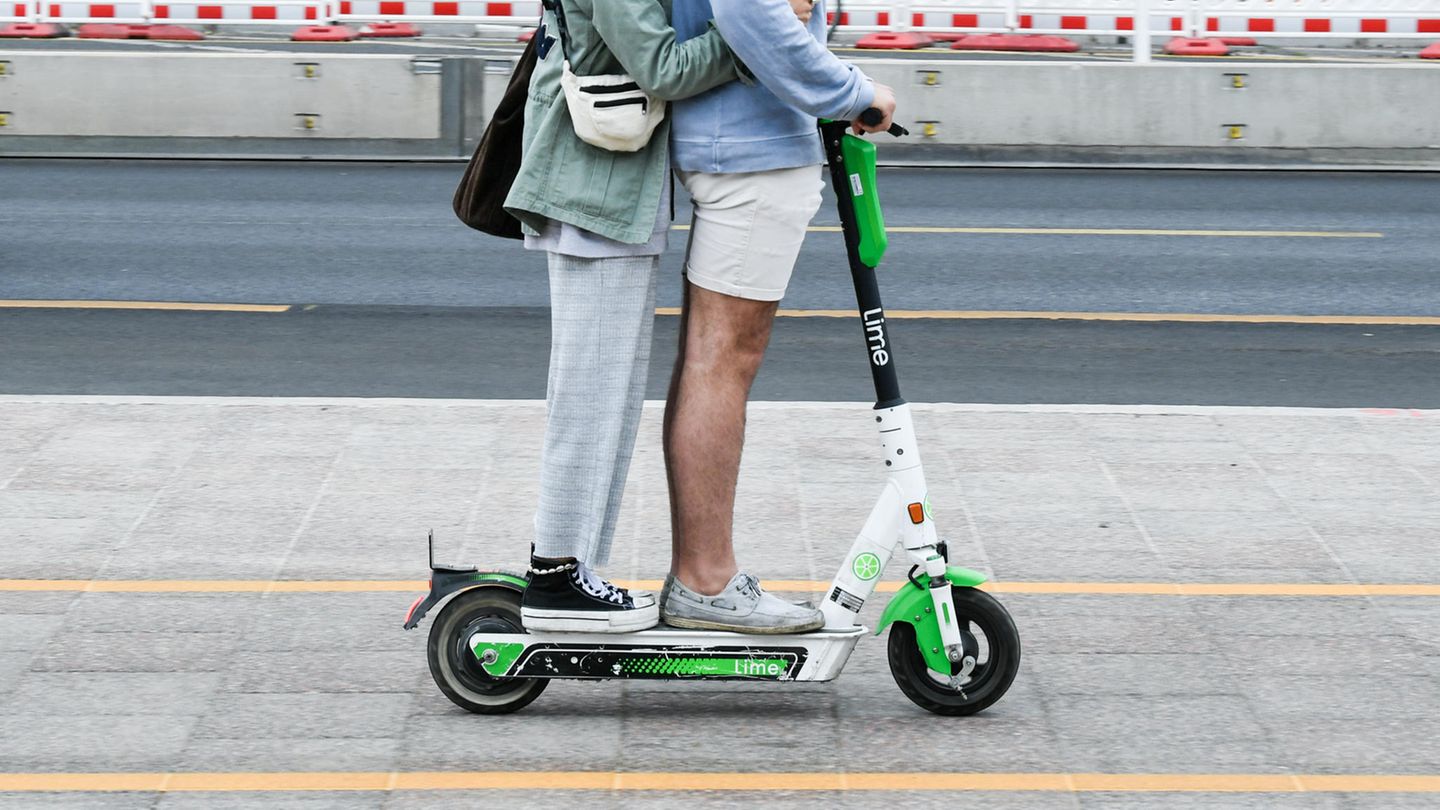 E-Scooter: Zwei junge Menschen fahren gemeinsam auf einem Roller