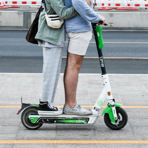 E-Scooter: Zwei junge Menschen fahren gemeinsam auf einem Roller