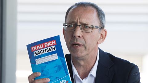 Jörg Urban, Vorsitzender der AfD in Sachsen, hält eine Broschüre mit der Aufschrift "Trau Dich Sachsen"